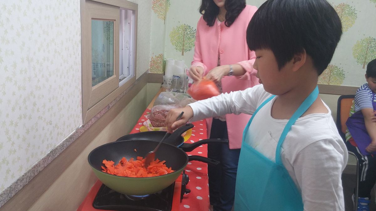 앞치마를 두르고 당근을 볶는 학생